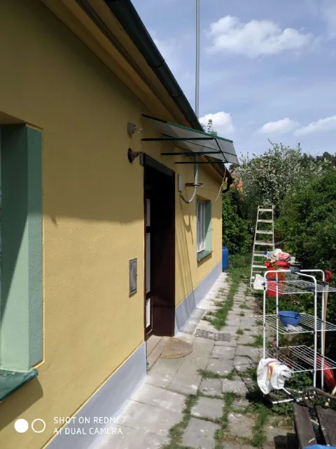 Nová žlutá fasáda rodinného domu se zelenými okenicemi